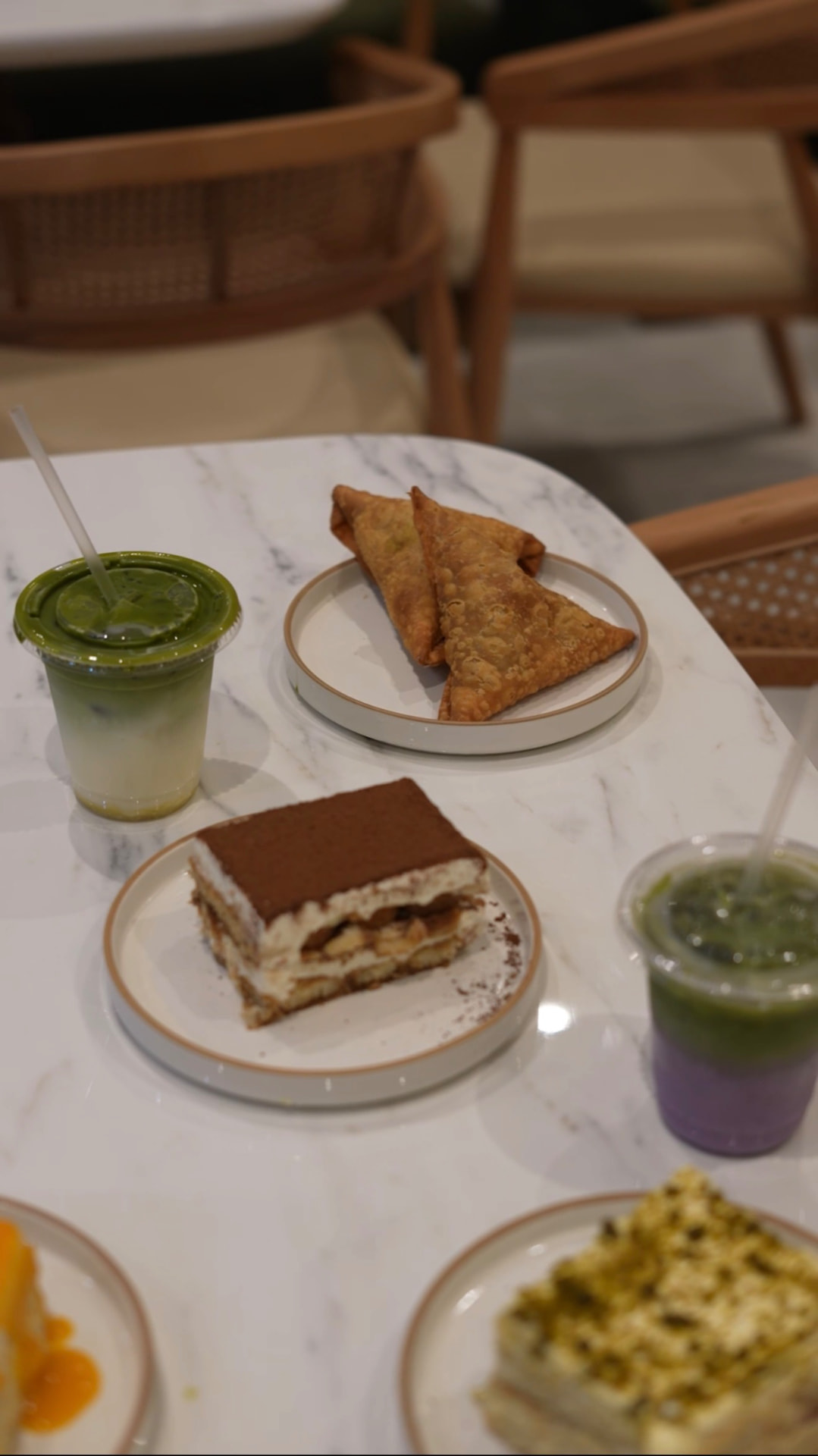 Tiramisu, sambusas and iced matcha on a marble table at MAICAFE